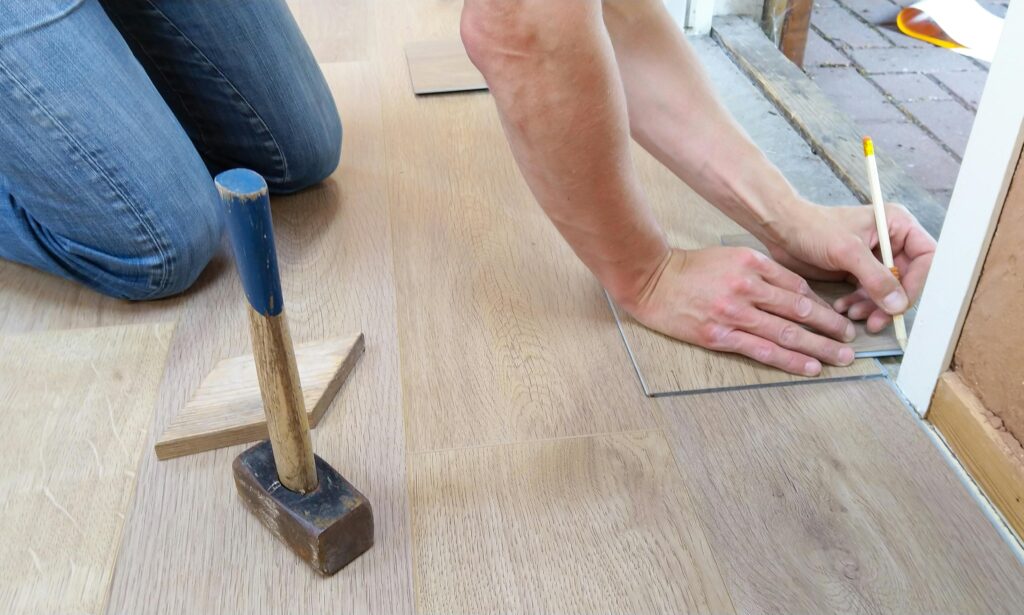 floor flooring hand man 1388944 1388944 A craftsman carefully measures and marks wooden floor panels for precise installation.